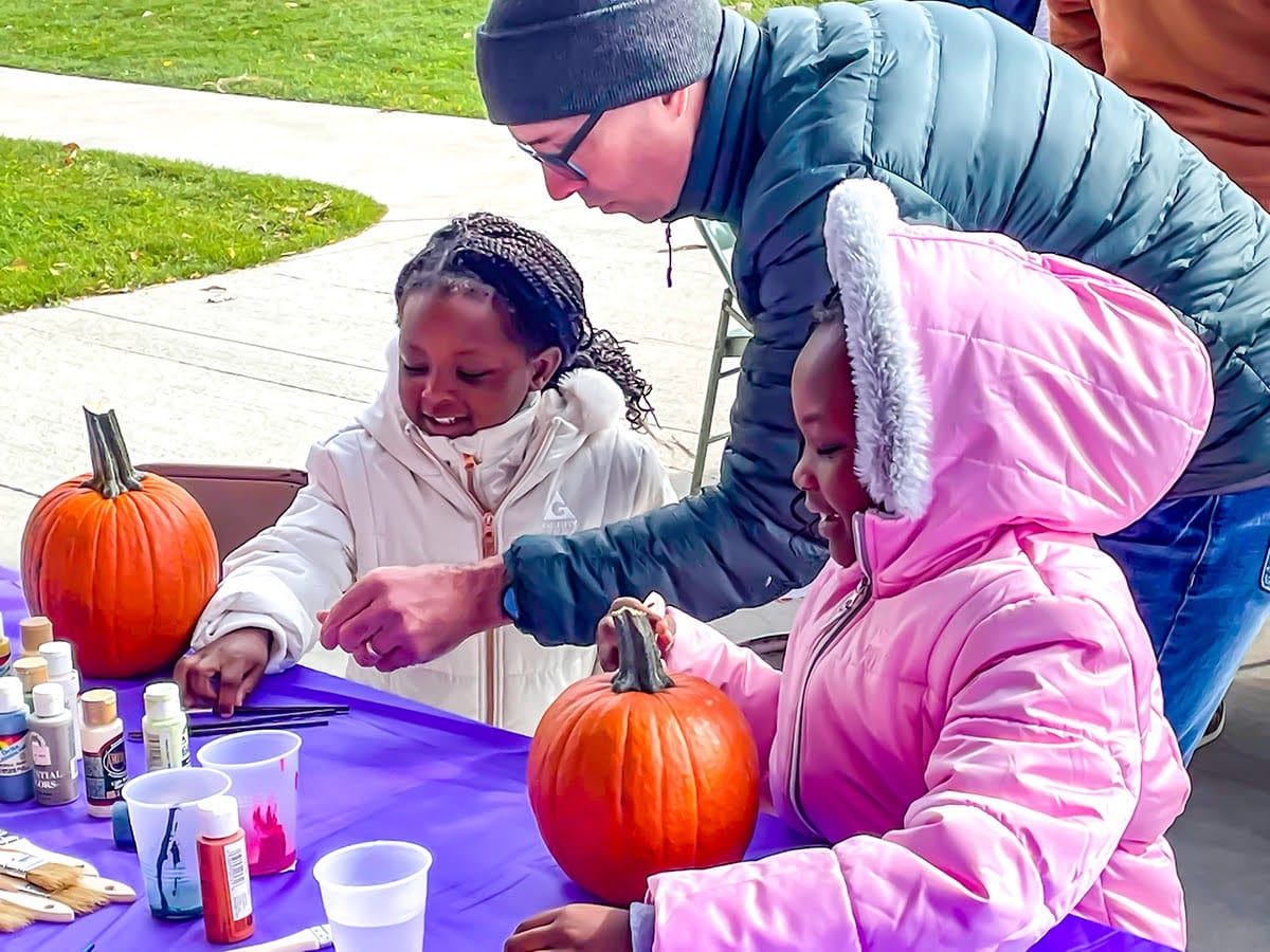 young girls get help decorating pumpkins